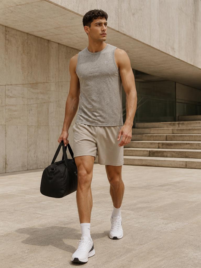 Model walking through a concrete plaza in a heather grey training tank and stone shorts